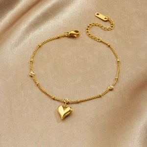 Elegant gold heart pendant bracelet with crystal accents on a champagne satin background
