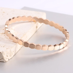 Detail of rose gold hexagonal honeycomb pattern on a polished minimalist metal bracelet