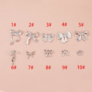 Dix pendentifs nœuds en acier inoxydable pour création de bijoux DIY sur fond rose