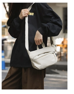 Detail of white nylon crossbody bag with adjustable wide strap shown on a model
