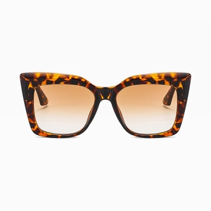 Macro detail of oversized cat-eye sunglasses with tortoise shell frame and brown gradient lenses