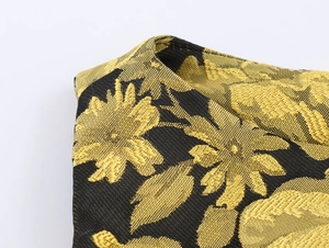 Primer plano de la textura de jacquard dorado y bordado en el vestido negro sin mangas