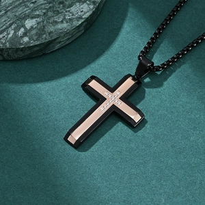 Men's two-tone black and rose gold cross necklace with crystal inlay on a dark background