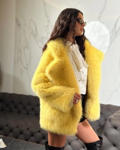 Detailed close-up of a bright yellow faux fur coat with a plush texture and lapel collar