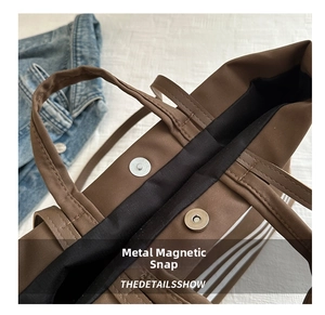 Close-up of magnetic snap closure on a brown canvas tote bag with black lining detail