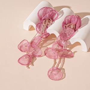 Macro detail of pink organza flower earrings with delicate beaded tassel and petal texture