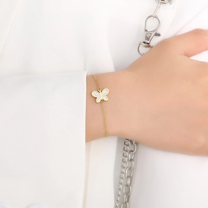 Detailed view of a gold butterfly bracelet with crystal pavé wings on a model wrist