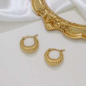 Detail of gold twisted hoop earrings on white silk and vintage frame background