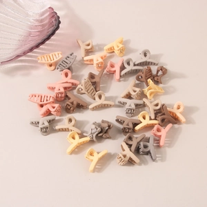 Detailed top view of assorted macaron colored mini hair claw clips on a neutral fabric