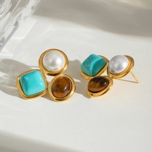 Detail view of geometric earrings with turquoise, pearl, and tiger eye stone in gold