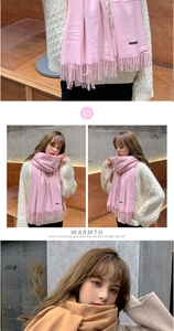 Close-up of soft knit winter scarf with fringe details in baby pink and camel tones