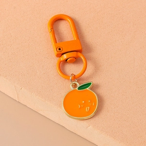 Close-up of cute smiling orange fruit pendant with leaf on a metal keychain hook
