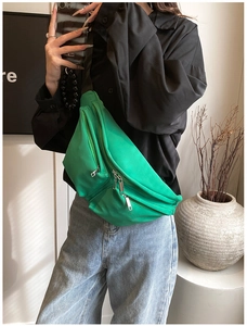 Detail of a green nylon crossbody chest bag showing zippers and durable fabric texture