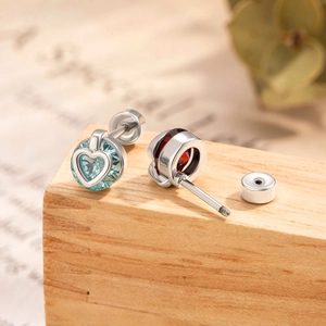 Hollow heart stud earrings with sparkling blue and red cubic zirconia on wood