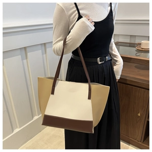 Gros plan d'un sac cabas en cuir tricolore crème et marron dans un décor intérieur élégant