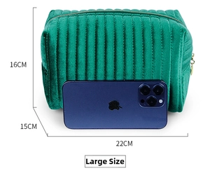 Close-up of a large green velvet cosmetic bag featuring vertical quilting and gold zipper