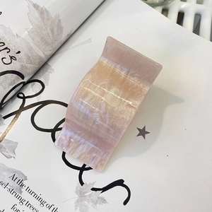 Detailed close-up of a pearlescent light pink marble acetate hair claw on a magazine