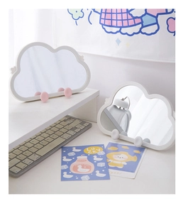 Detail of irregular cloud-shaped makeup mirror with hooks on a minimalist desk setup
