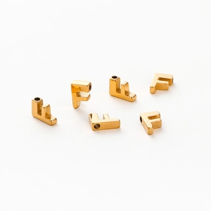Macro view of six gold-plated letter F charms with smooth finish and 1.8mm holes