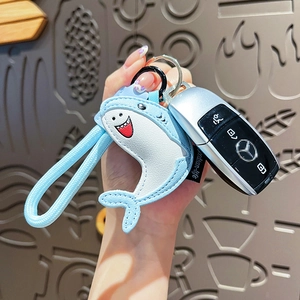 Porte-clés requin en cuir bleu clair tenu à la main avec fermoir en métal poli