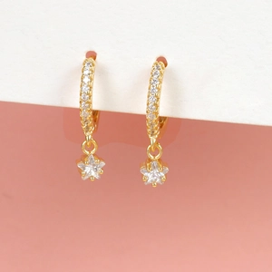 Chic gold star hoop earrings with sparkling crystal pavé on pink and white background
