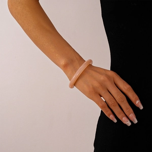 Detailed view of a pink resin bangle with marble texture on a model's wrist