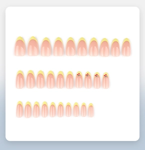 Detail view of 30pcs almond fake nails with yellow French tips and 3D cherry patterns