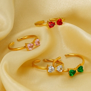 Golden titanium steel bow rings with colorful zircon inlay on luxury silk fabric