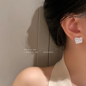Élégantes boucles d'oreilles argentées asymétriques à texture irrégulière sur modèle