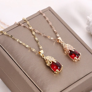 Close-up of titanium steel Pixiu necklaces in gold and rose gold with red gemstones