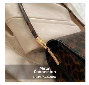 Close-up of the polished gold metal buckle and leopard print strap on the handbag