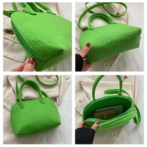 Detail view of bright green shell bag with embossed crocodile texture and inner space
