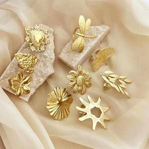 Set of gold stainless steel rings featuring nature elements on a silk and stone background