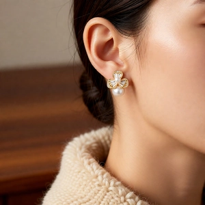 Close-up of elegant flower pearl earrings worn on ear with knit sweater background