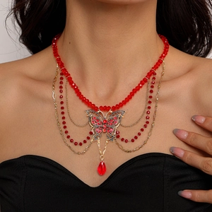 Détail d'un collier papillon de luxe avec perles rouges et chaînes dorées sur un mannequin