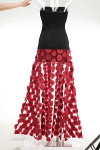 Detailed view of black strapless bodice and red mesh skirt with 3D polka dot appliques
