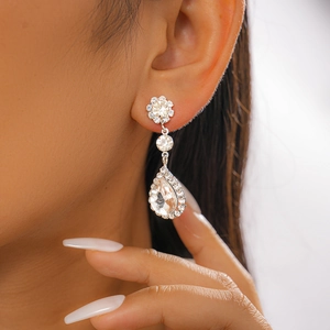 Détail de boucles d'oreilles argentées en goutte d'eau avec cristaux sur un mannequin