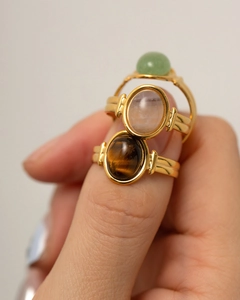 Close-up of stacked gold rings featuring oval tiger eye, rose quartz and aventurine stones