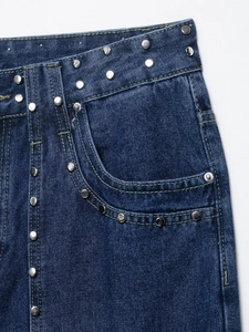 Détail de la taille en jean bleu foncé avec clous argentés et coutures de précision