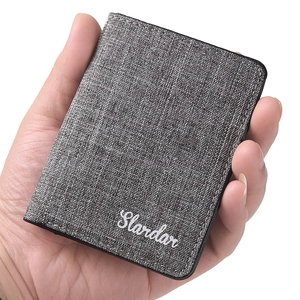 Slim canvas bifold wallet in dark grey held in hand, minimalist ultra-thin card holder