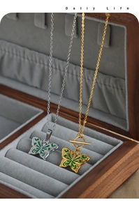 Détail macro de pendentifs papillon en émail vert sur un support en velours