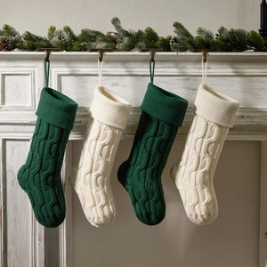 Set of 4 knitted Christmas stockings in forest green and cream on fireplace