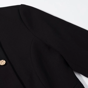 Dettaglio di un blazer nero strutturato con bottoni dorati goffrati di alta qualità