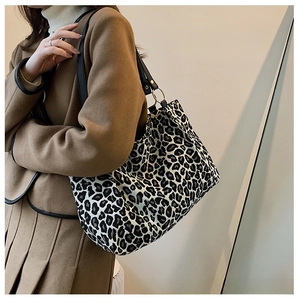 Model wearing a large leopard print canvas tote bag with black straps and gold rings