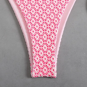 Detailed macro view of pink crochet lace fabric with hollow diamond patterns on a bikini
