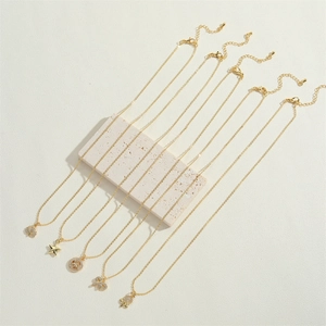 Detailed close-up of five gold necklaces with star and shell pendants on a stone base