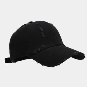 Close-up of distressed details and frayed edges on a black cotton twill baseball cap
