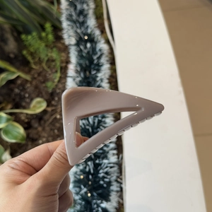 Detail of a geometric triangular matte purple hair claw clip held in hand