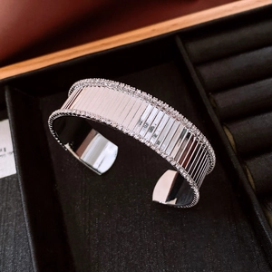 Dettaglio di un bracciale rigido argentato con strisce verticali e bordi di strass