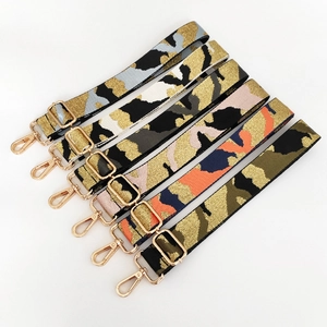 Macro detail of six camouflage woven bag straps with gold metal hooks and glitter yarn